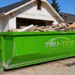 Tru-Tex green roll-off dumpster at a home renovation site